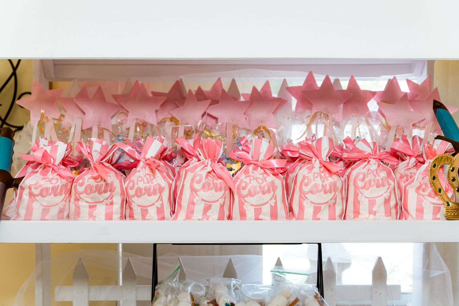 A row of pink party favor bags arranged neatly on a shelf with decorative elements.