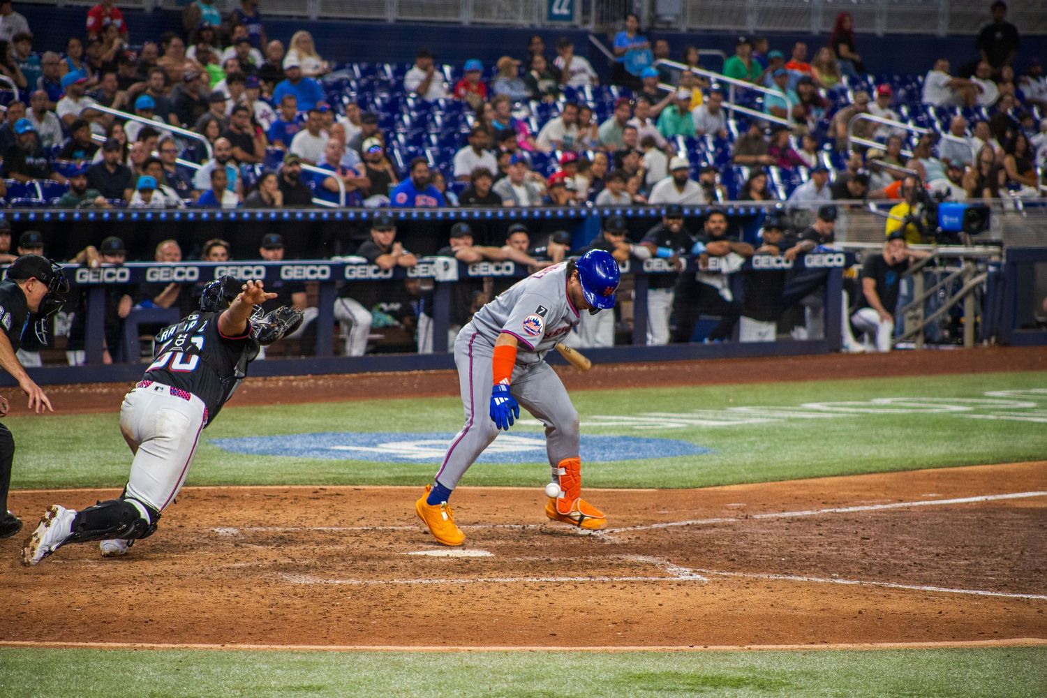 Baseball player slides into home plate during intense game action while catcher attempts to make the tag.