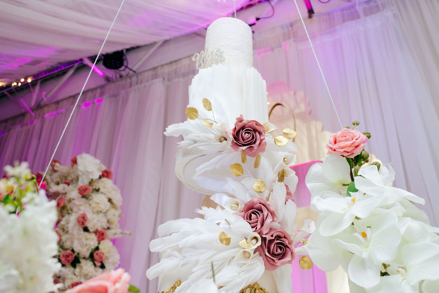 Elegant white tiered wedding cake decorated with pink roses and floral accents.