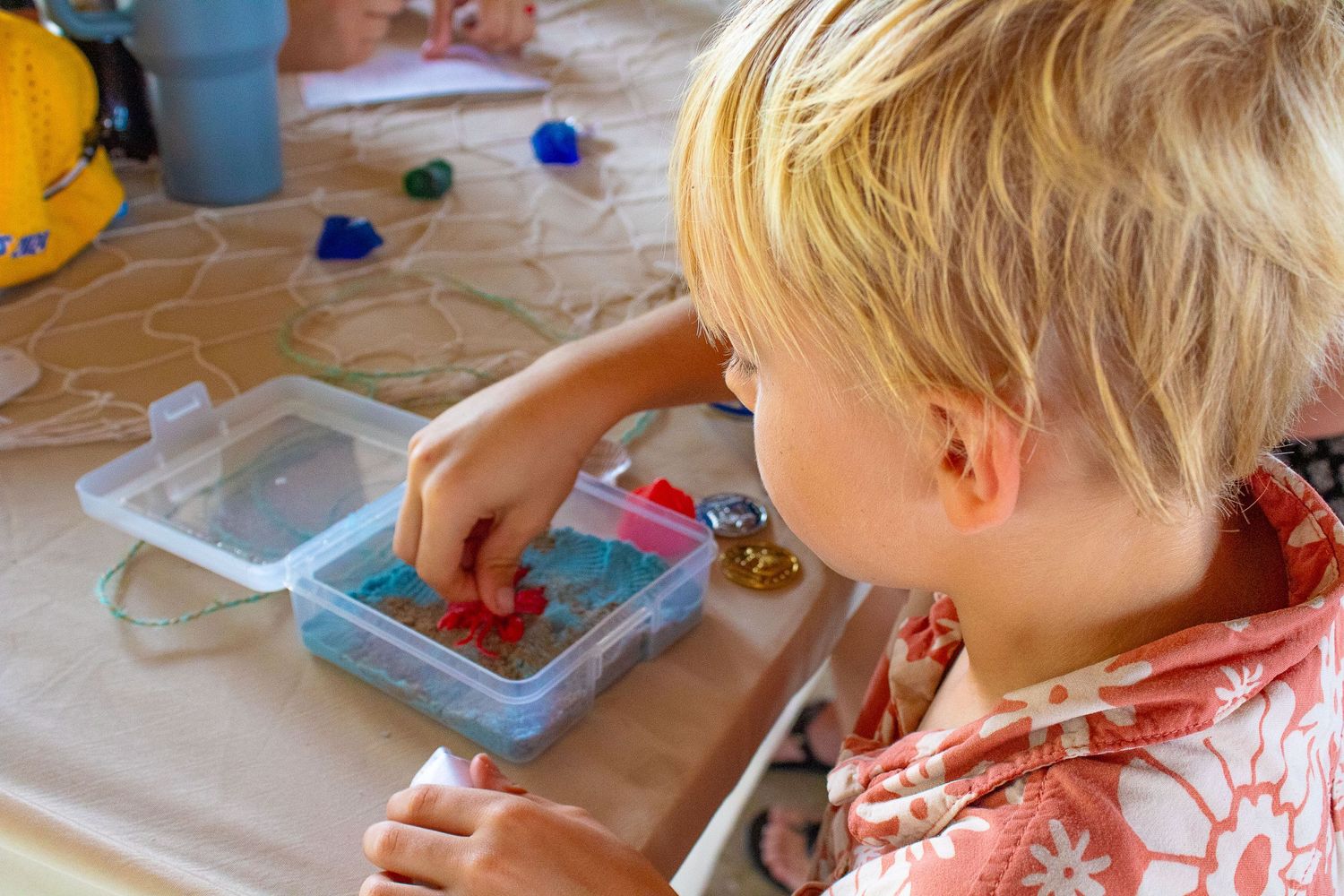 Young child doing arts and crafts activity at table with craft supplies.