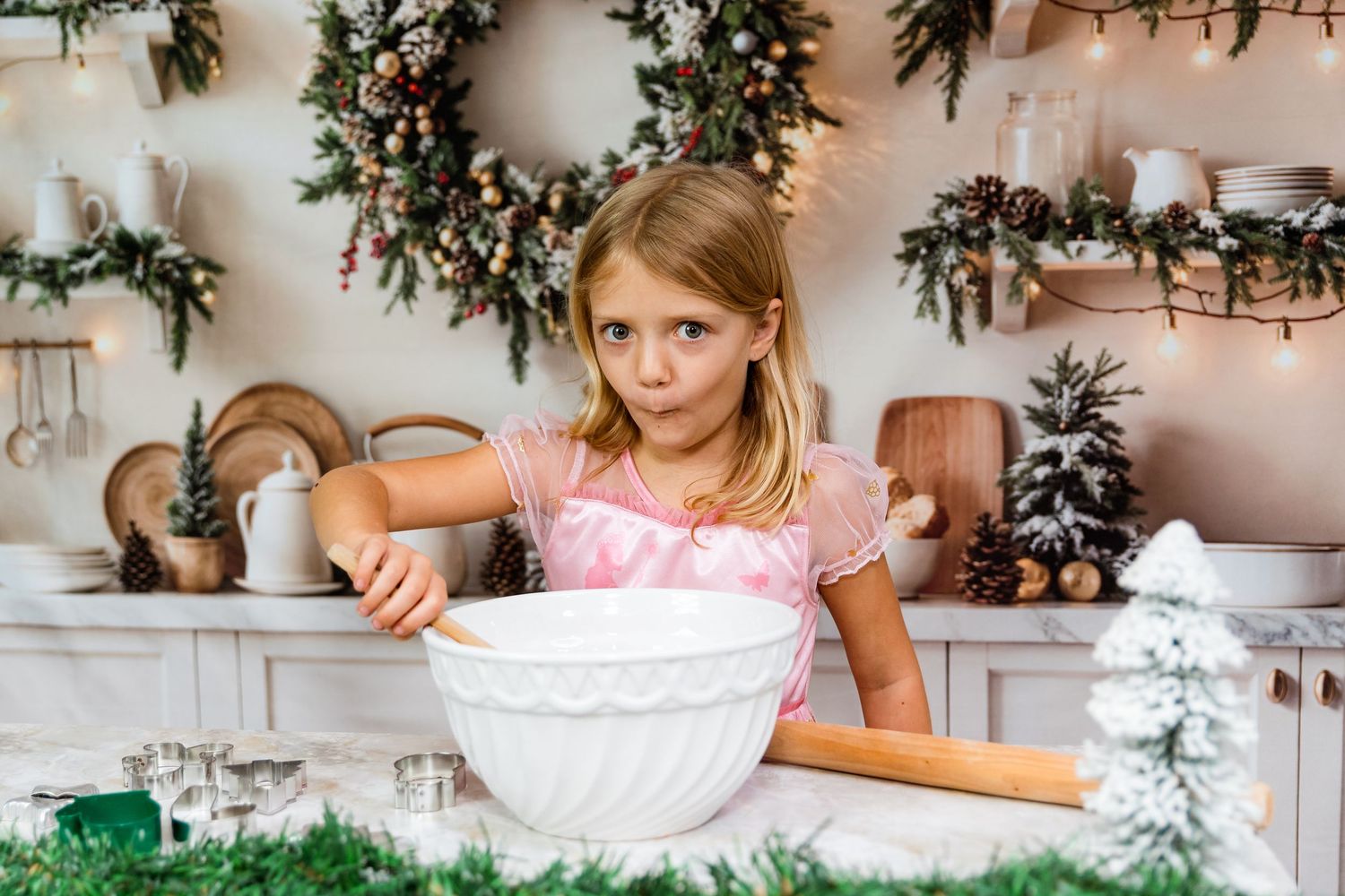 Young baker mixing ingredients in white bowl with holiday decorations and wreaths on wall.