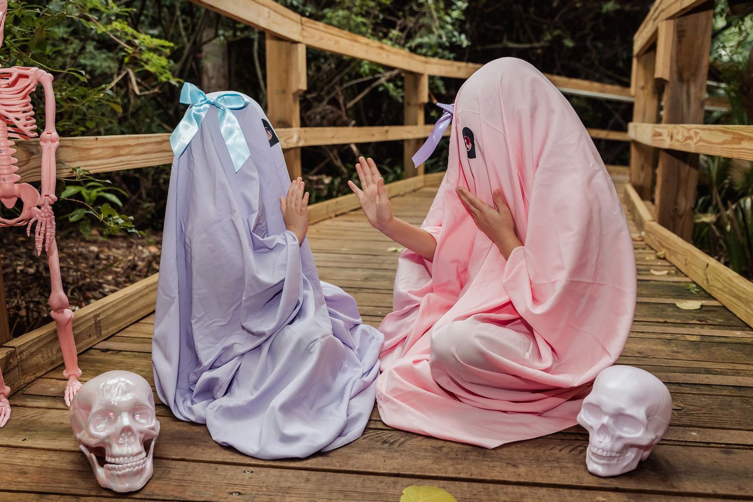 Group of people in traditional Muslim clothing sitting on wooden deck surrounded by nature and greenery.