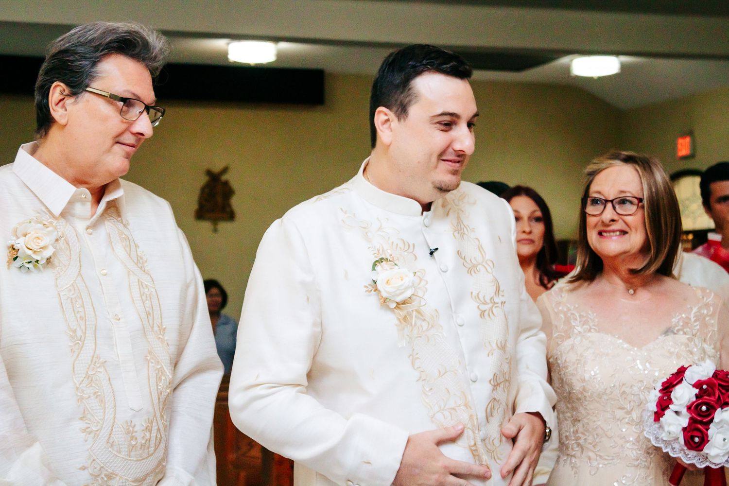 Wedding party members in white and cream formal attire standing together during ceremony.