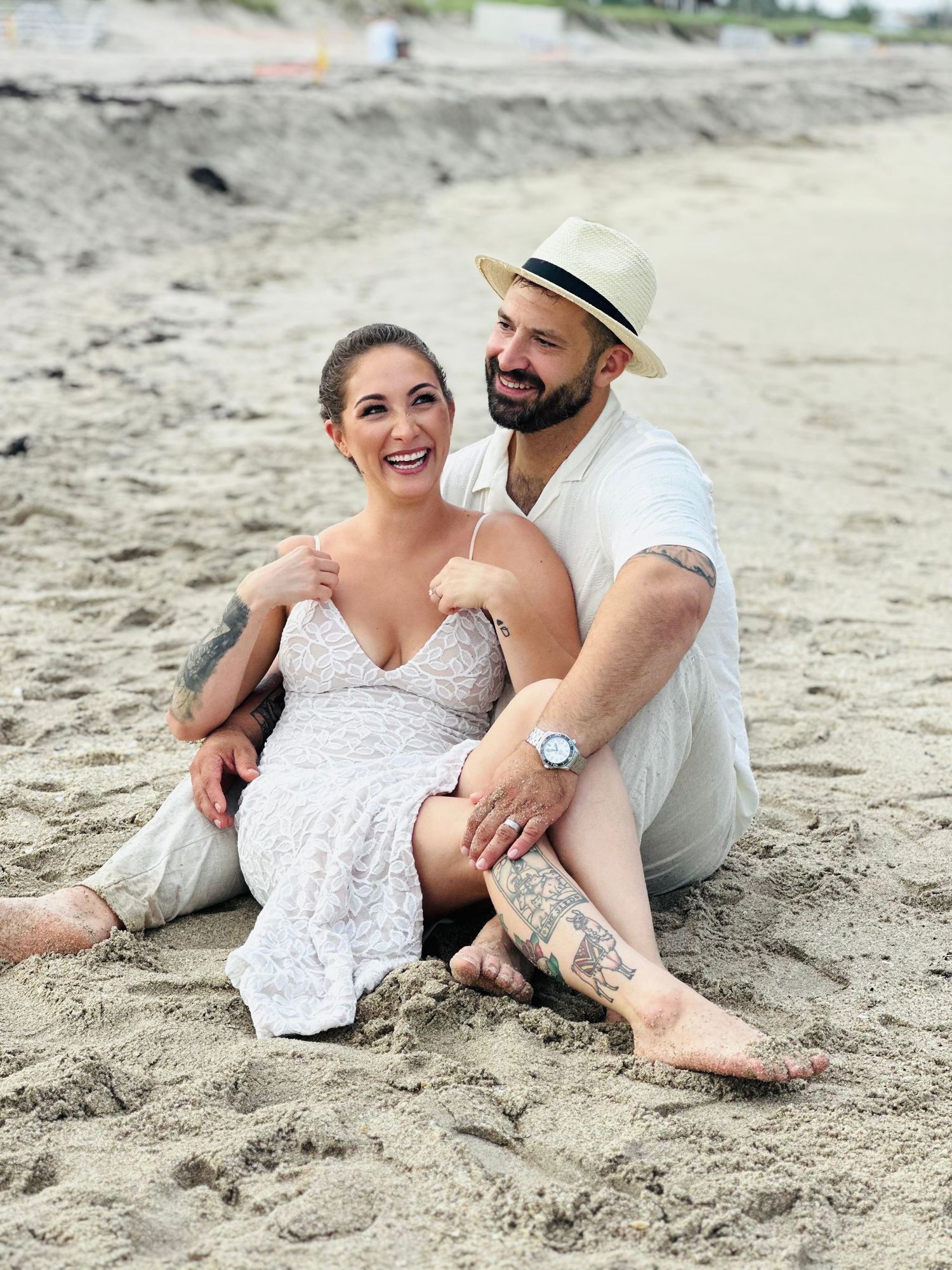 Happy couple sitting together on beach sand sharing an intimate moment.