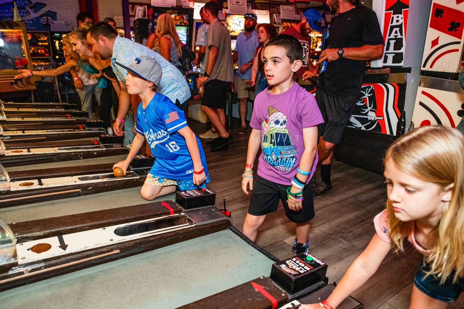 A group of children playing arcade games in a lively, colorful gaming environment.