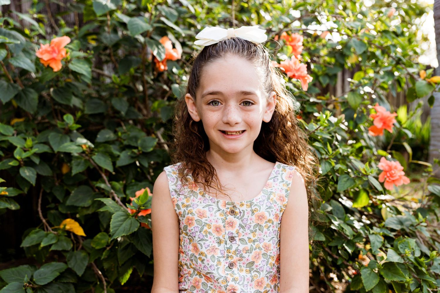 Spring portrait with coral roses blooming in background garden setting.