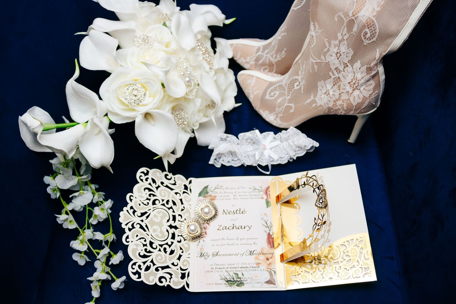 Elegant wedding details featuring a white floral bouquet, lace bridal shoes, and an ornate laser-cut invitation with gold accents.