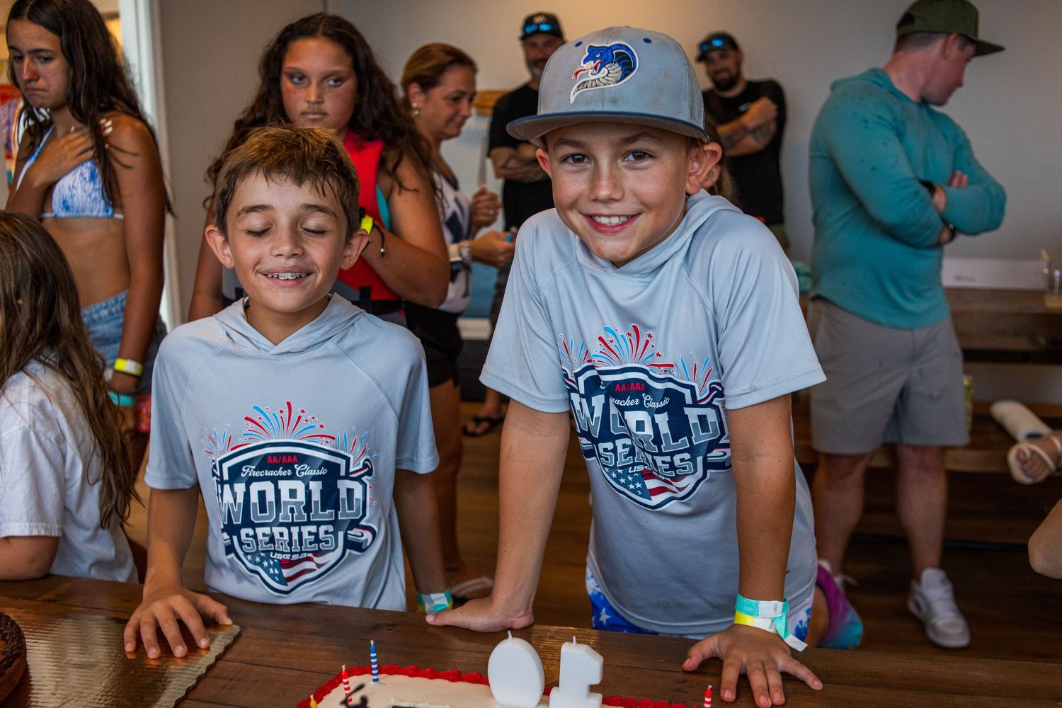 Two young people in matching gray t-shirts and team logos smile while sitting at a table together.