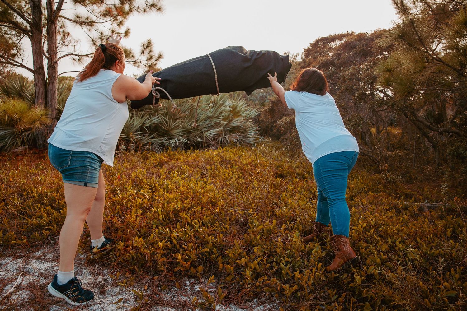 Person in blue tank top and shorts bending over in autumn foliage during outdoor photo sequence.