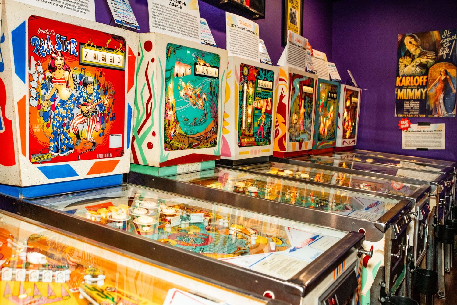 A colorful display of vintage pinball machines in an arcade setting.