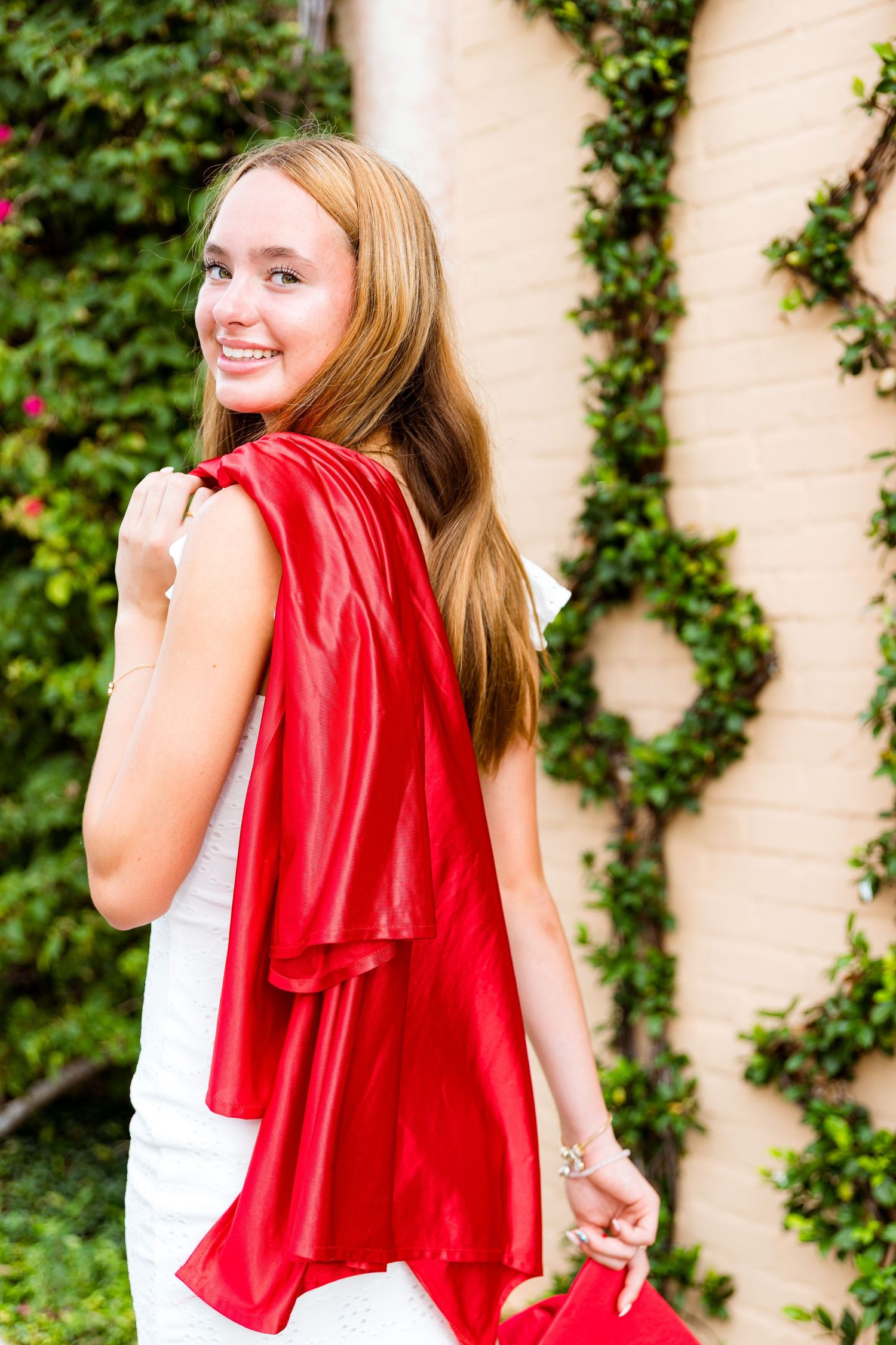 A portrait against a wall with climbing ivy vines featuring a flowing red fabric accent.