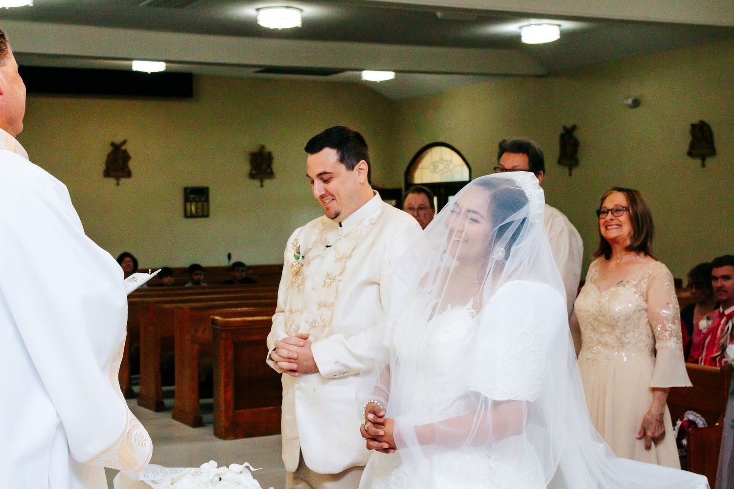A row of wedding guests in formal attire seated at tables during a reception celebration.