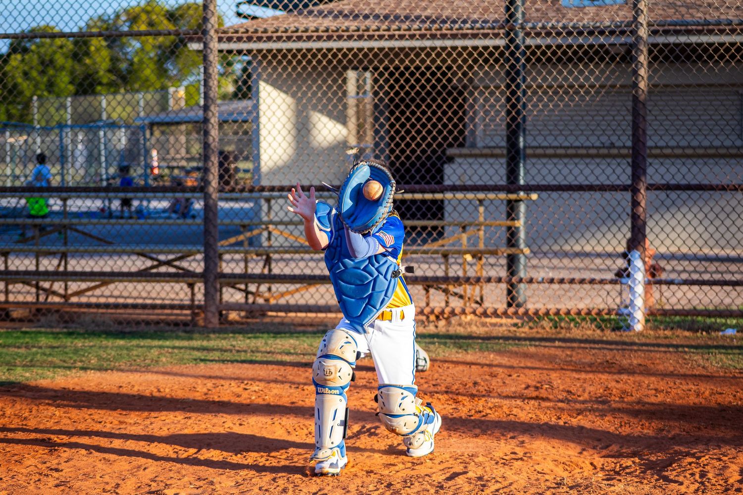 Youth baseball player in blue and white uniform takes batting stance on dirt field during practice.