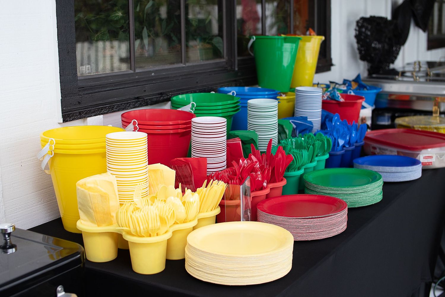 Colorful plastic party supplies including plates, cups and utensils arranged on a table.