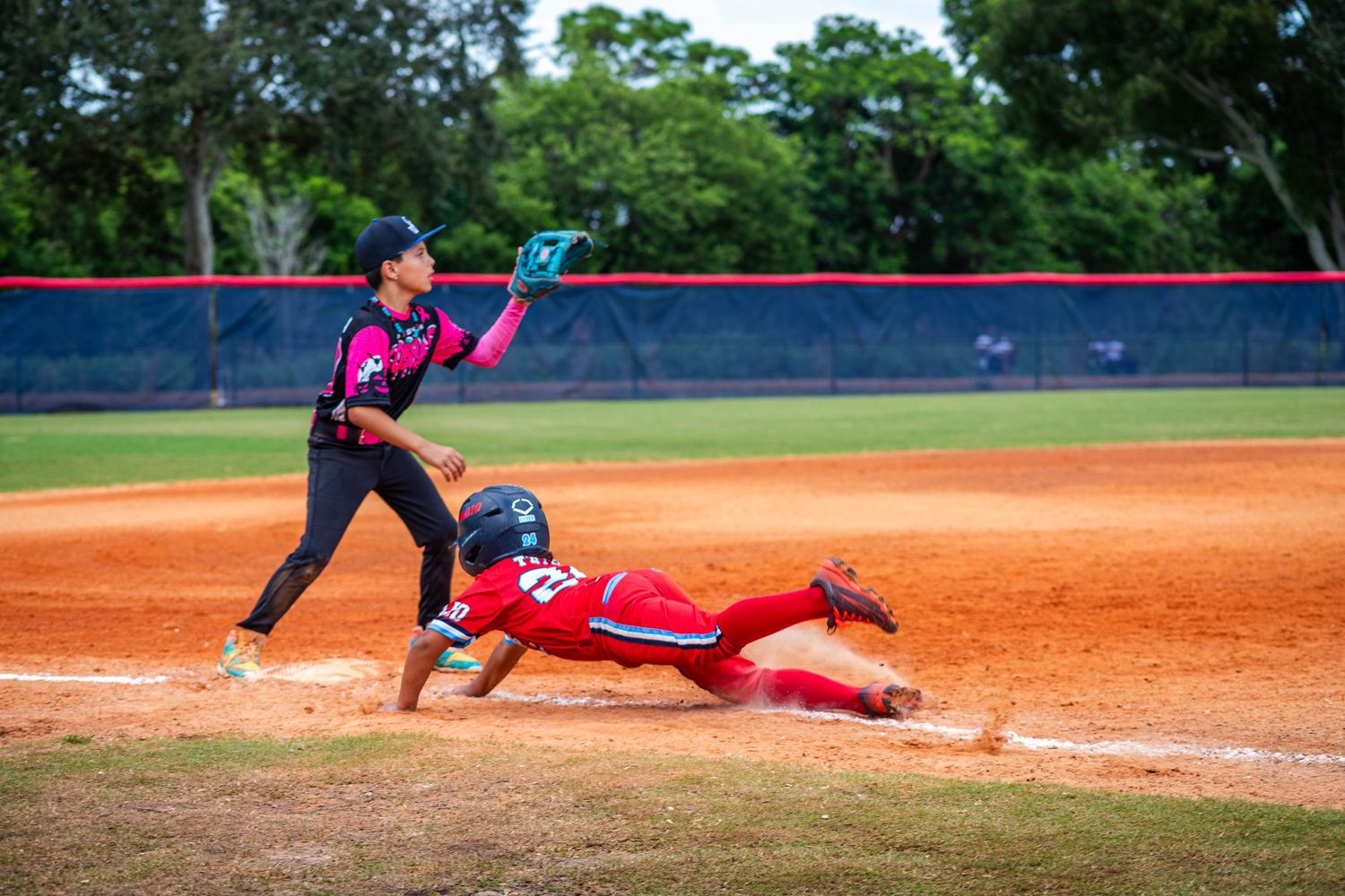 Baseball player slides into base while fielder reaches to make the tag during competitive game action.