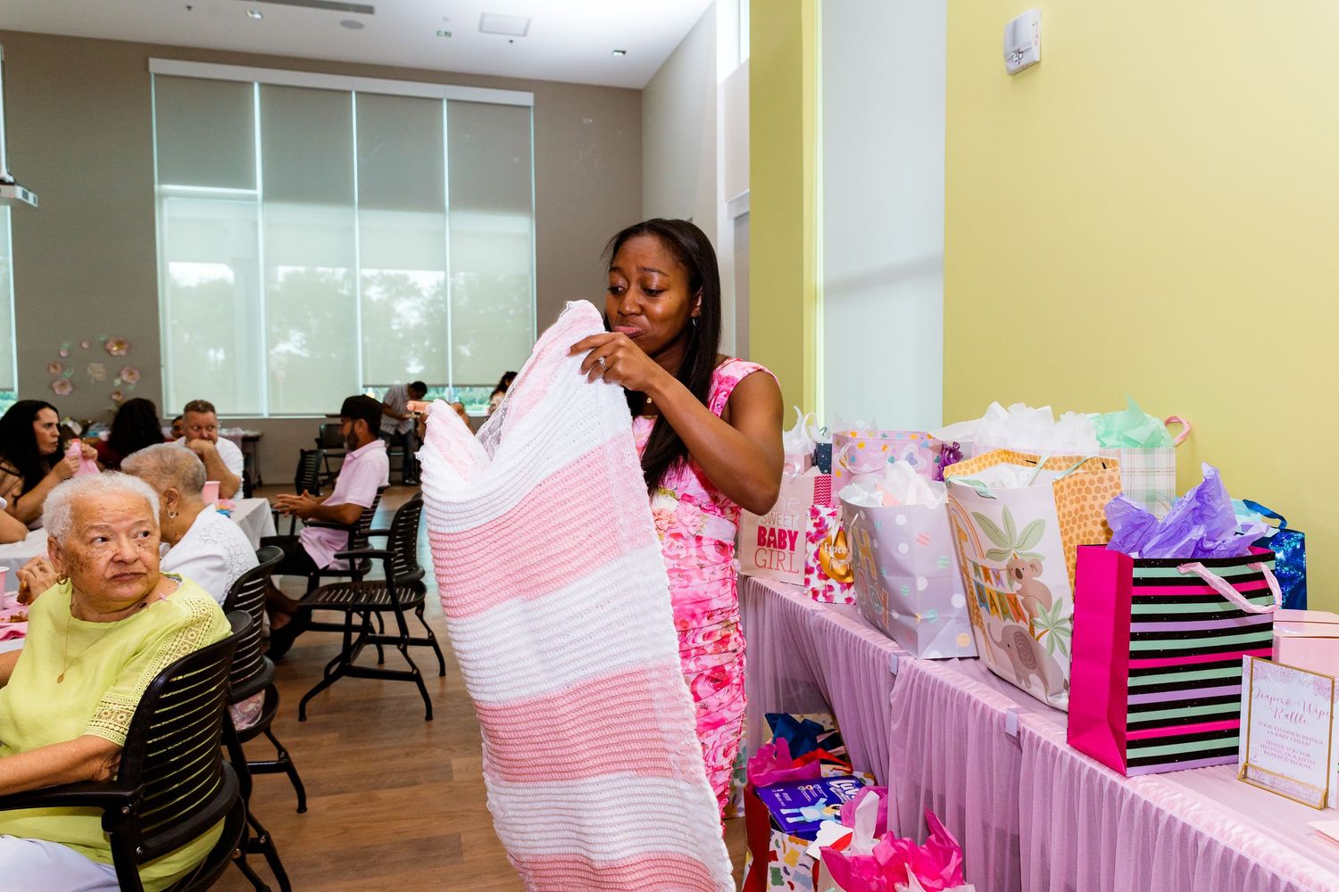 Guest examines pink and white striped gift items at a celebration event.