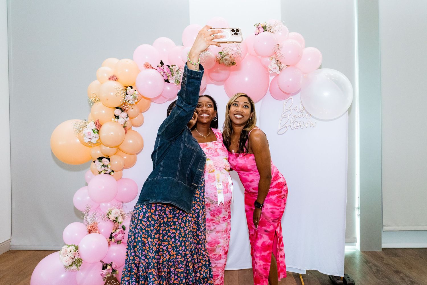 Group celebrating under decorative balloon arch at indoor event.
