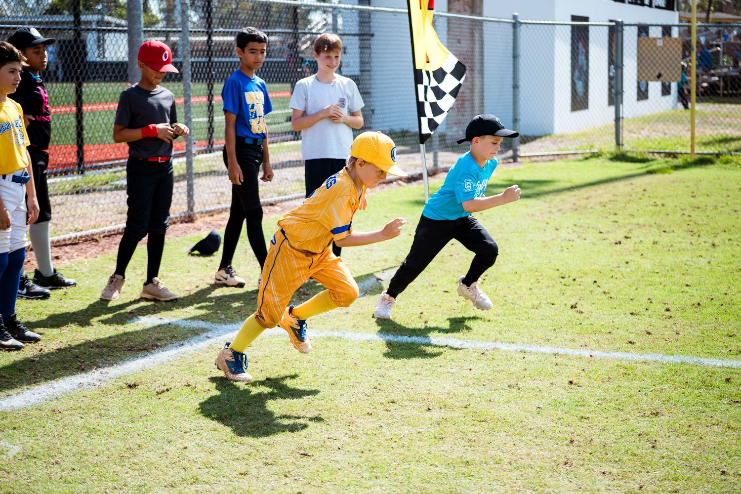 Children participate in a running race competition on a grassy field during an outdoor sports event.