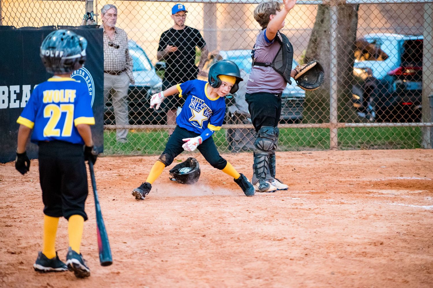 Young baseball player in blue uniform takes a low batting stance at home plate during a youth league game.