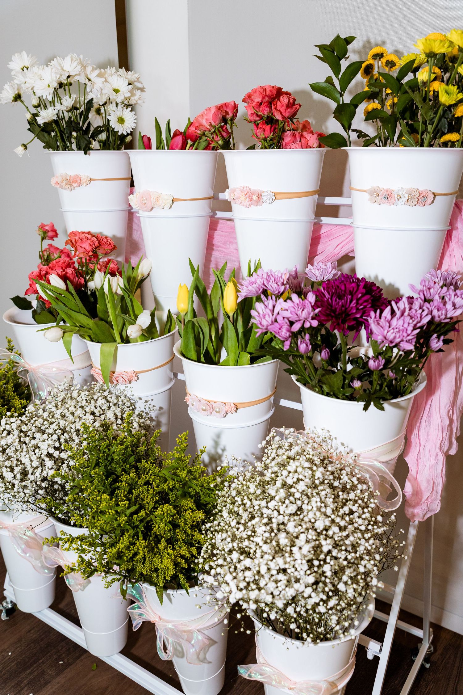 Beautiful arrangement of colorful flowers including carnations, chrysanthemums and baby's breath in white decorative pots.