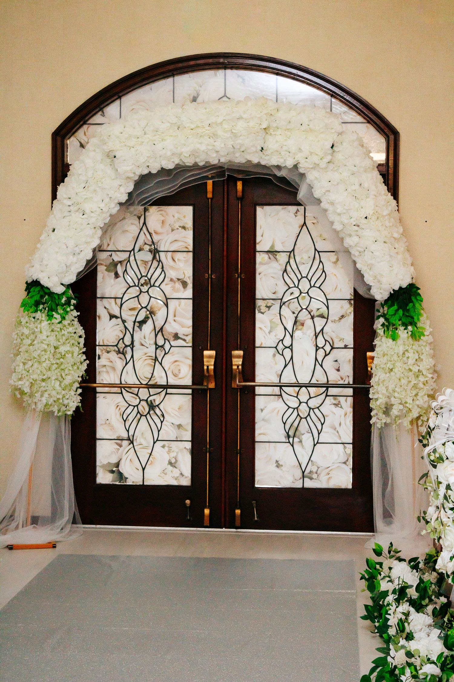 Arched doorway decorated with white floral arrangements and elegant iron detailing.