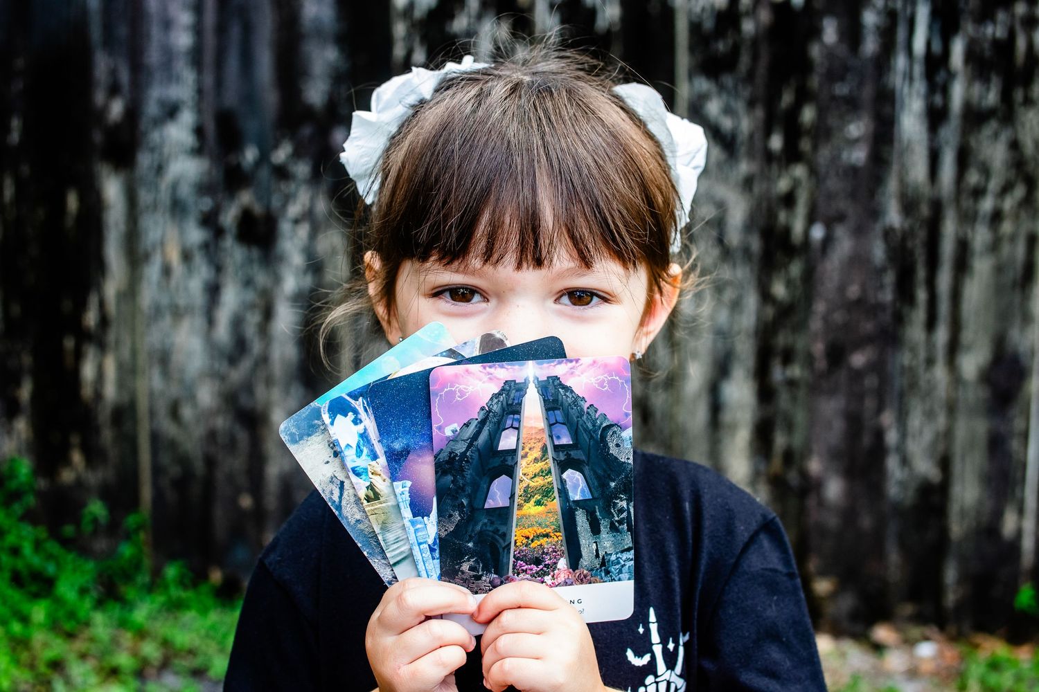 Child holding mystical tarot cards against dark rustic background.
