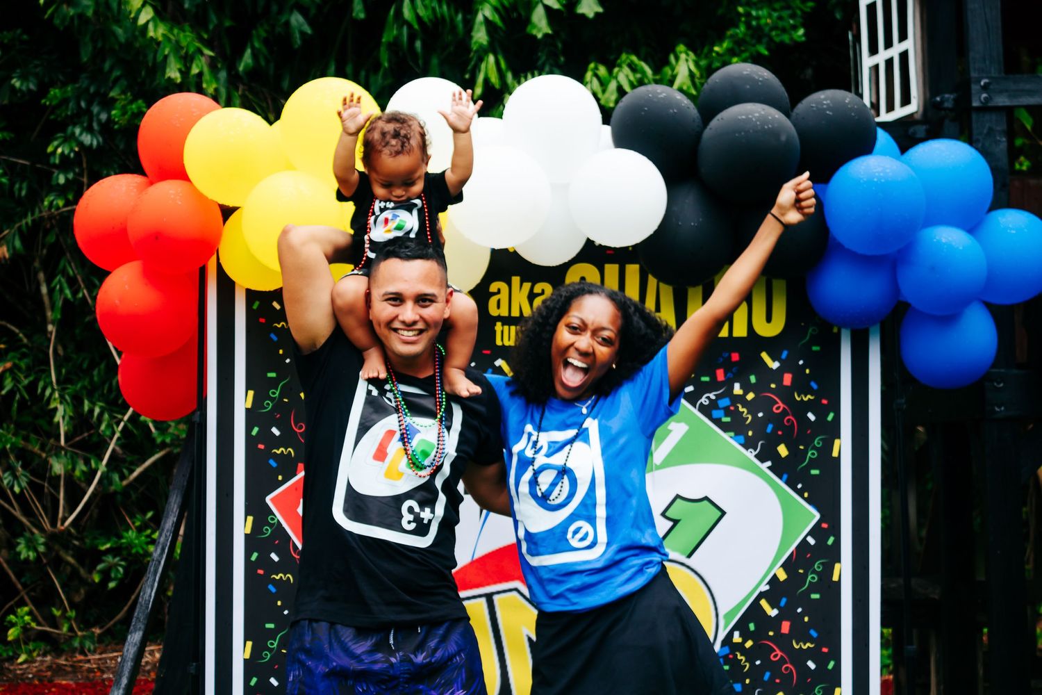 Party setup with rainbow balloon arch and UNO-themed decorations.