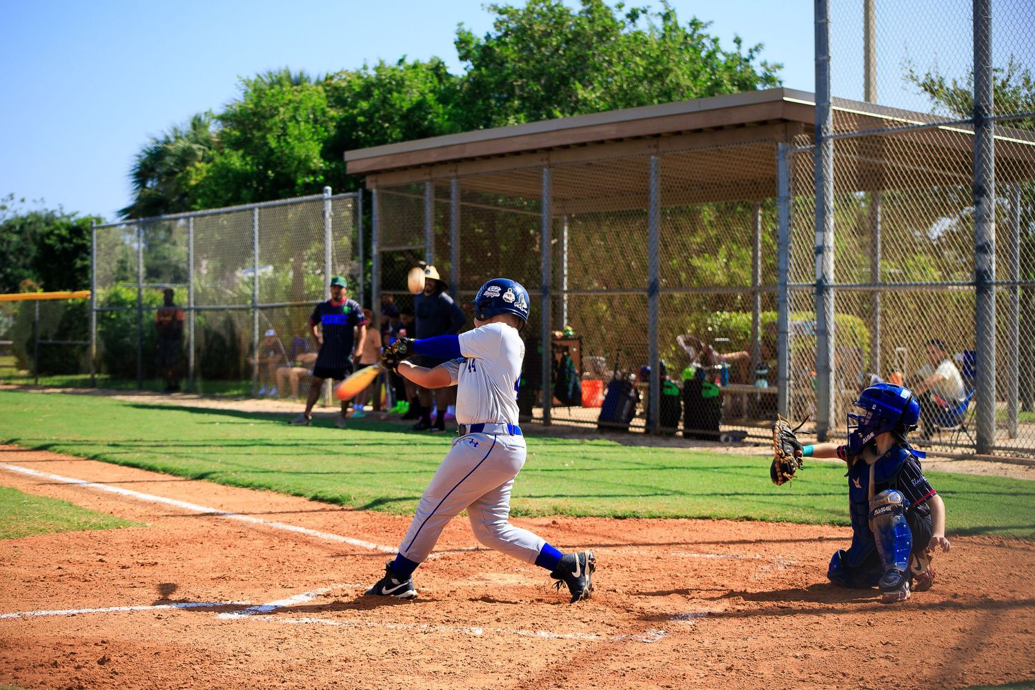 Baseball player swinging bat at home plate during competitive game on dirt field.