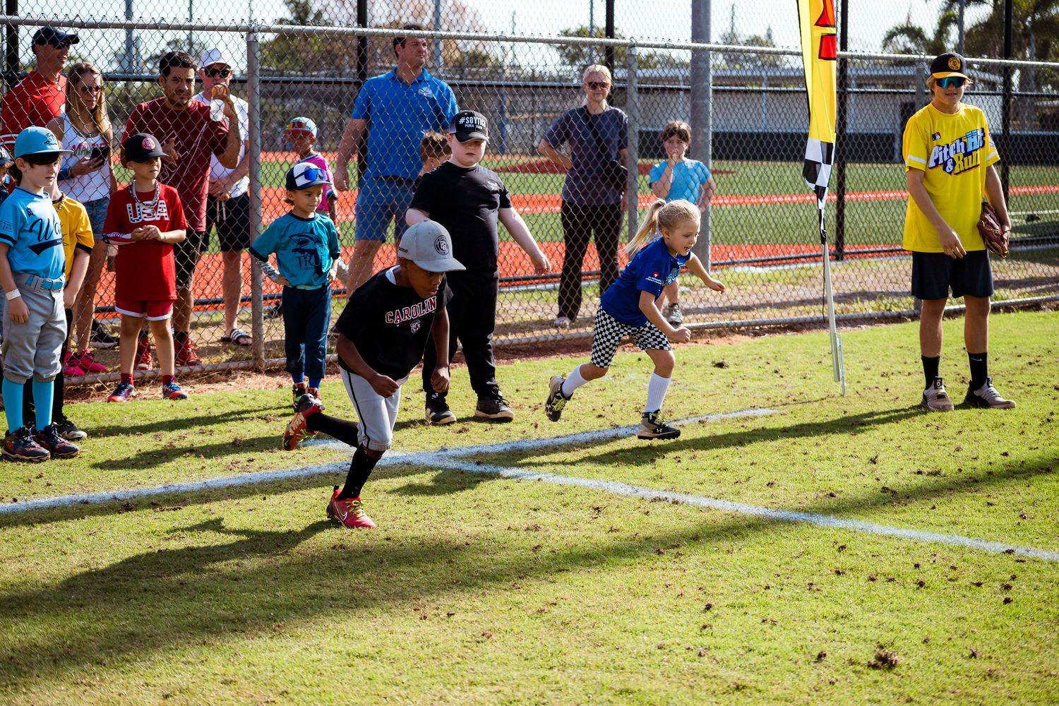 Young athletes running drills on a sunny sports field during a training session.