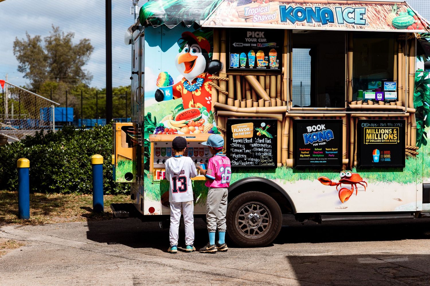 Customers wait at a colorful ice cream and dessert food truck decorated with vibrant murals and palm trees.