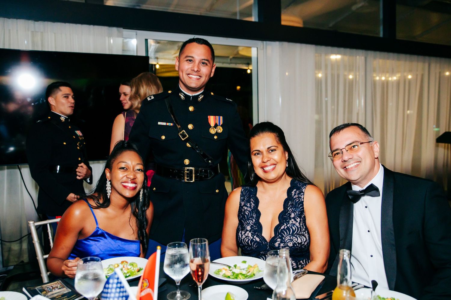Guests enjoying dinner and conversation at elegant banquet tables during formal evening event.