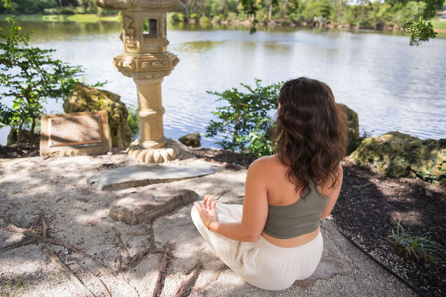 Two people share a romantic moment by a serene lake, surrounded by trees and natural beauty at sunset.