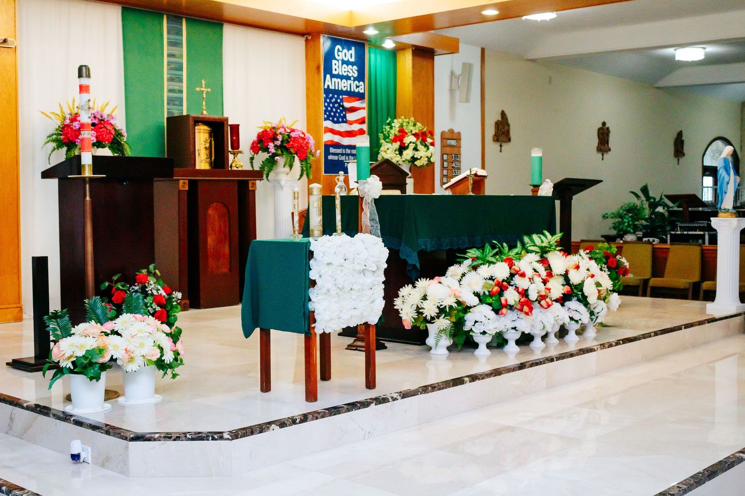 Church interior decorated with white and green floral arrangements for a wedding ceremony.