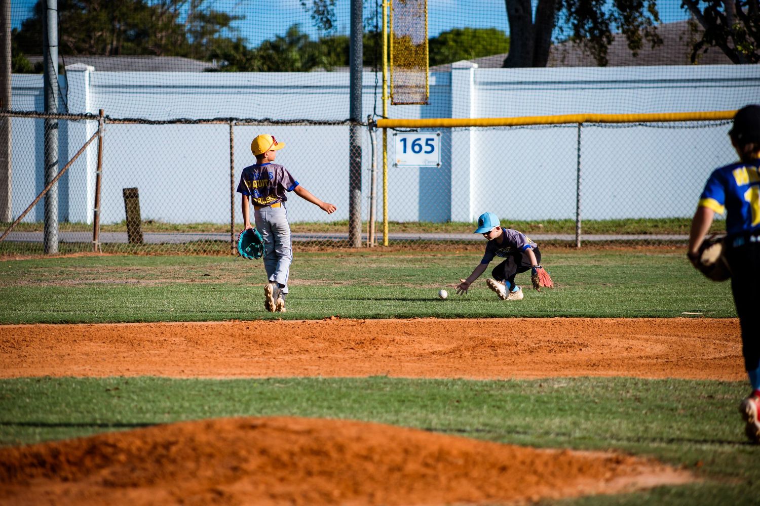 Baseball players in action on a dirt and grass diamond during a game with one player leaping off the pitcher's mound.