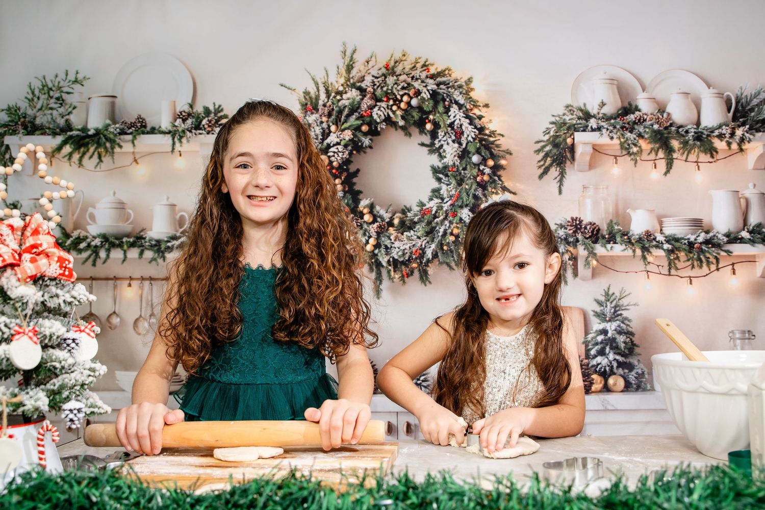 Two young children sit at a decorated table making Christmas crafts together with festive decor in the background.