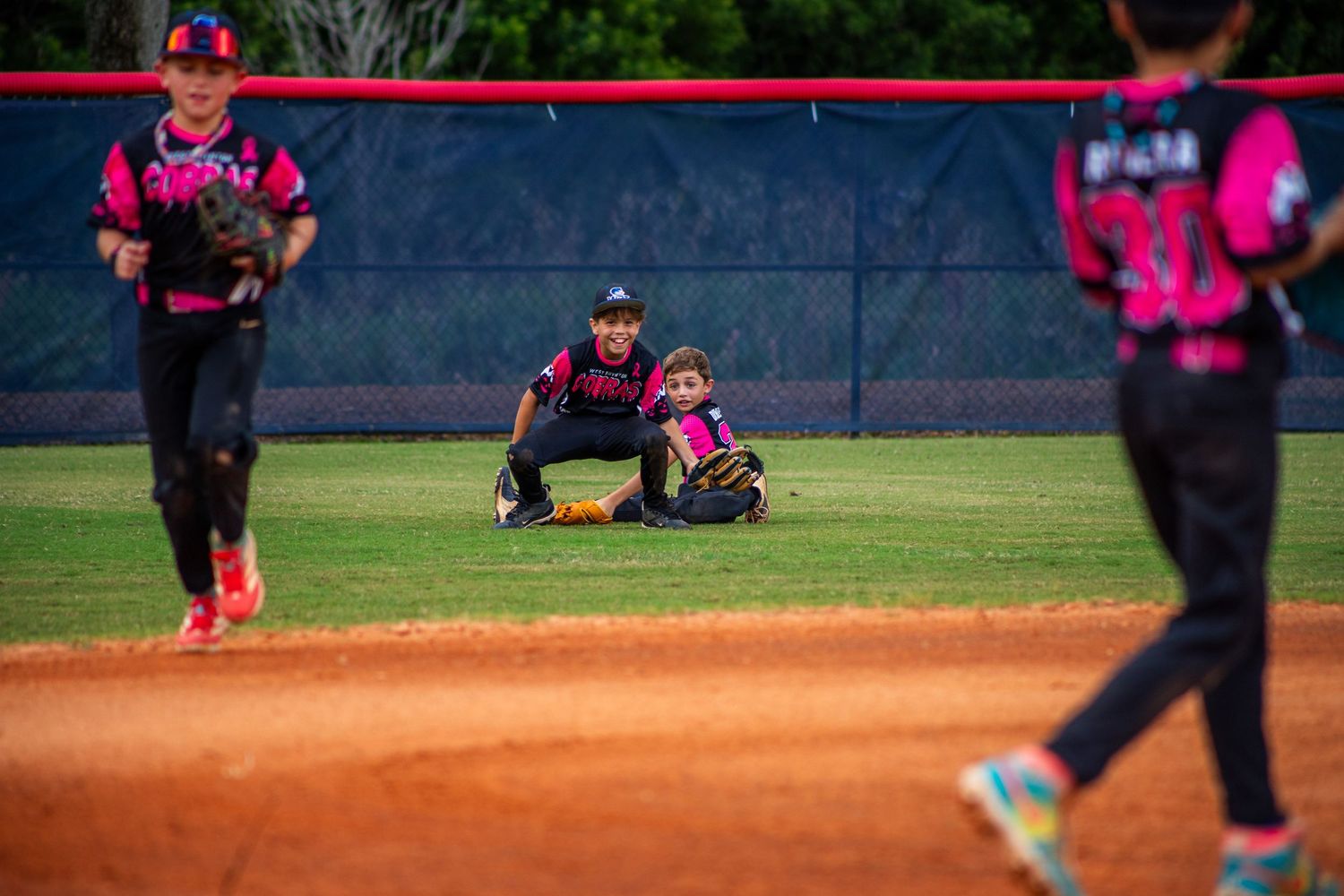 Baseball players in bright pink uniforms positioned across the infield during a game.