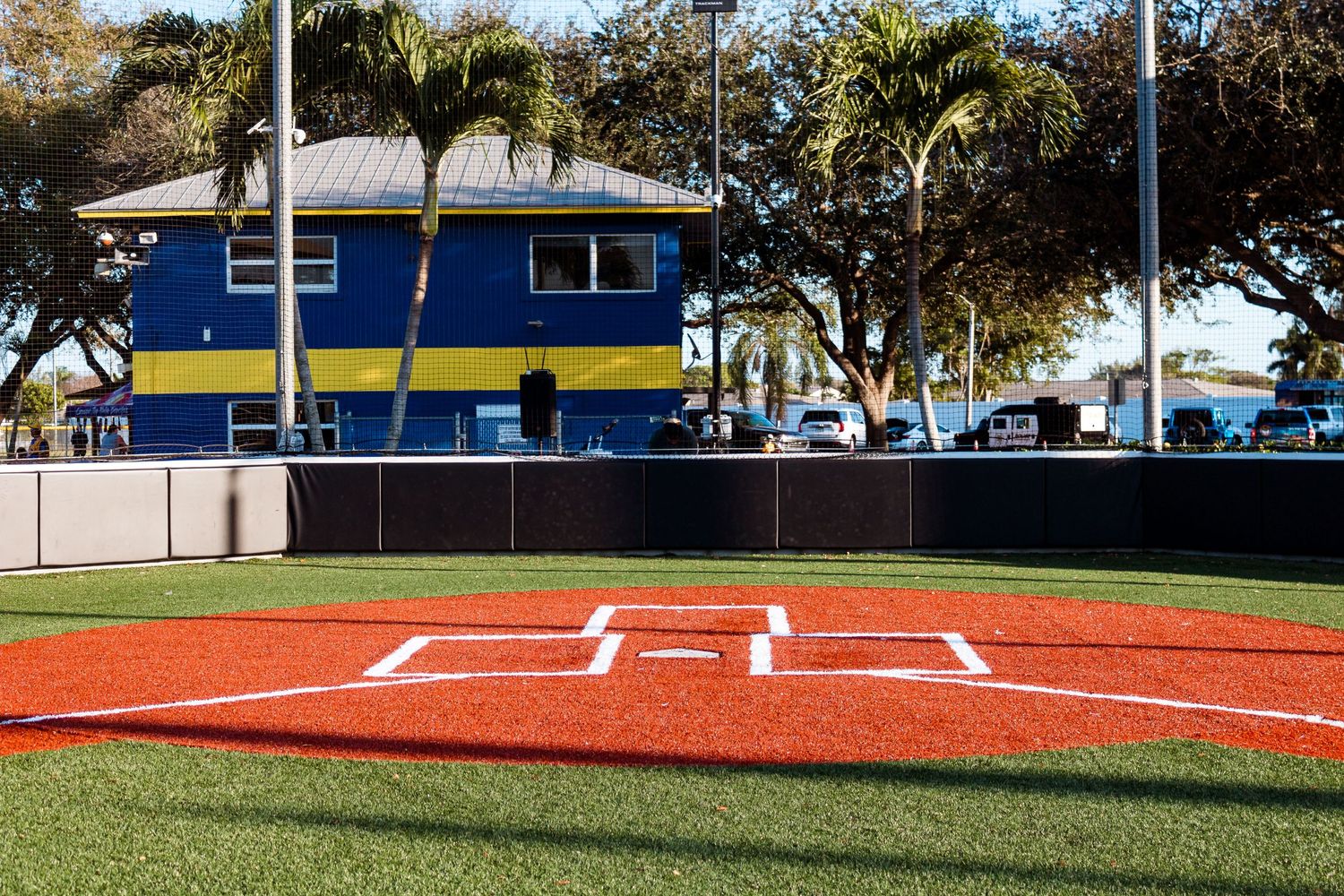 Baseball field with blue building in background and home plate in foreground.