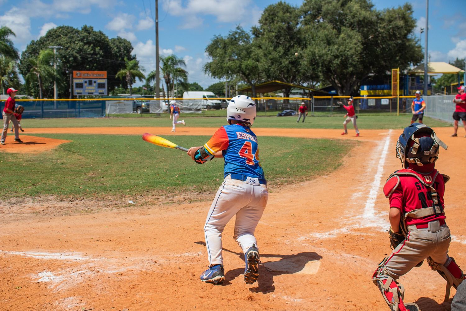Youth baseball batter at home plate with catcher during sunny afternoon game.