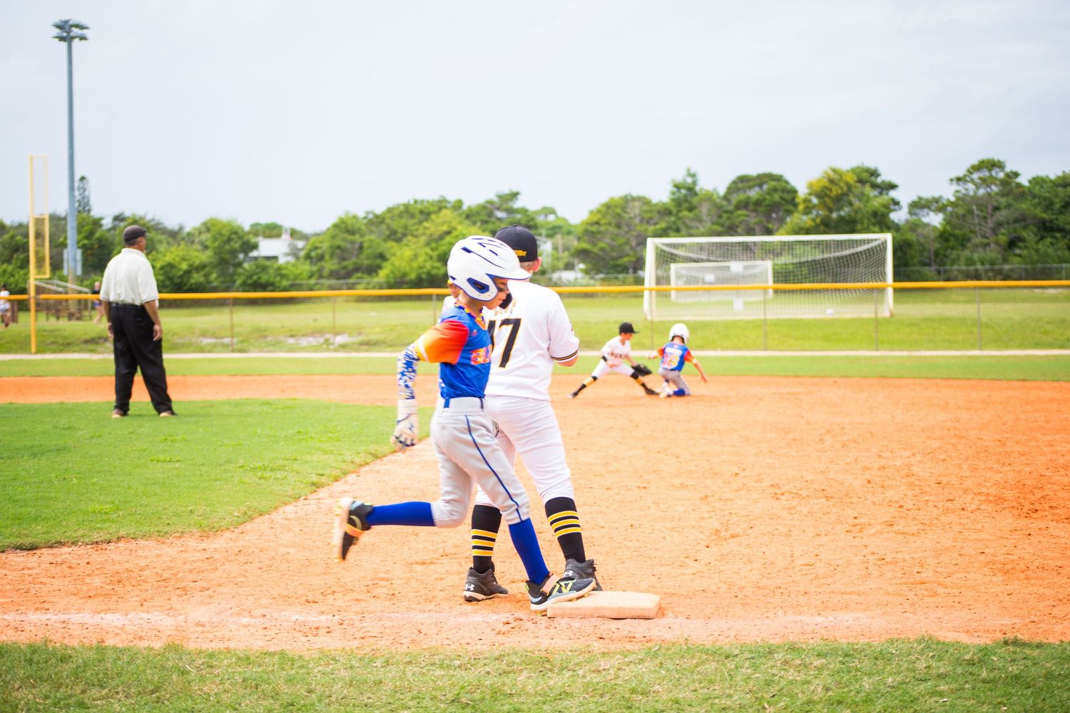 Baseball runner sprinting towards first base during competitive game play.