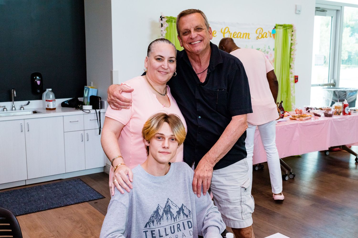 Family group photo at a celebration with pink party decorations.