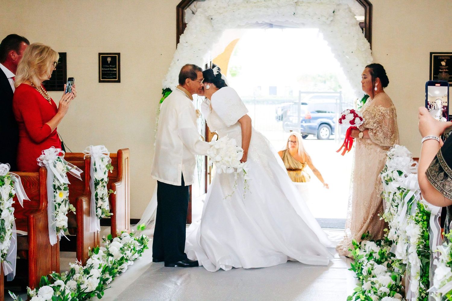 Newlyweds celebrate down a winding staircase decorated with greenery and white floral arrangements.