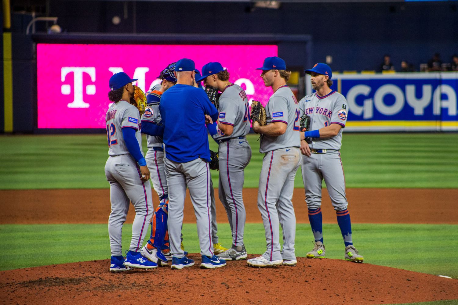 Baseball team huddled on pitcher's mound during game conference.