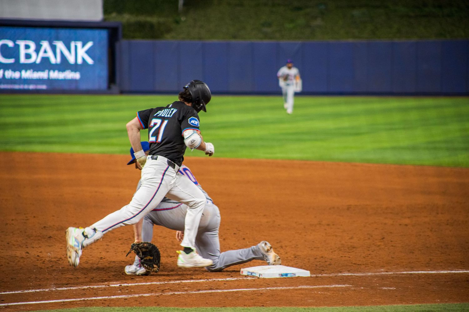 Baseball player sliding into base during close play at professional stadium.