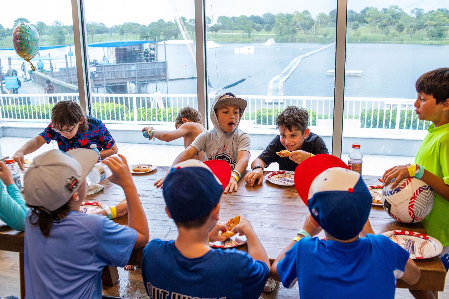 Group of people sitting at picnic tables enjoying refreshments under an outdoor pavilion.
