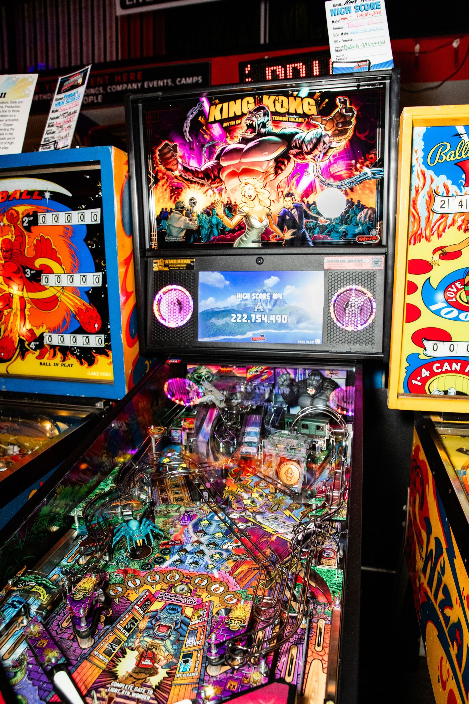 A colorful and vibrant pinball machine with various lights and graphics is displayed in an arcade setting.