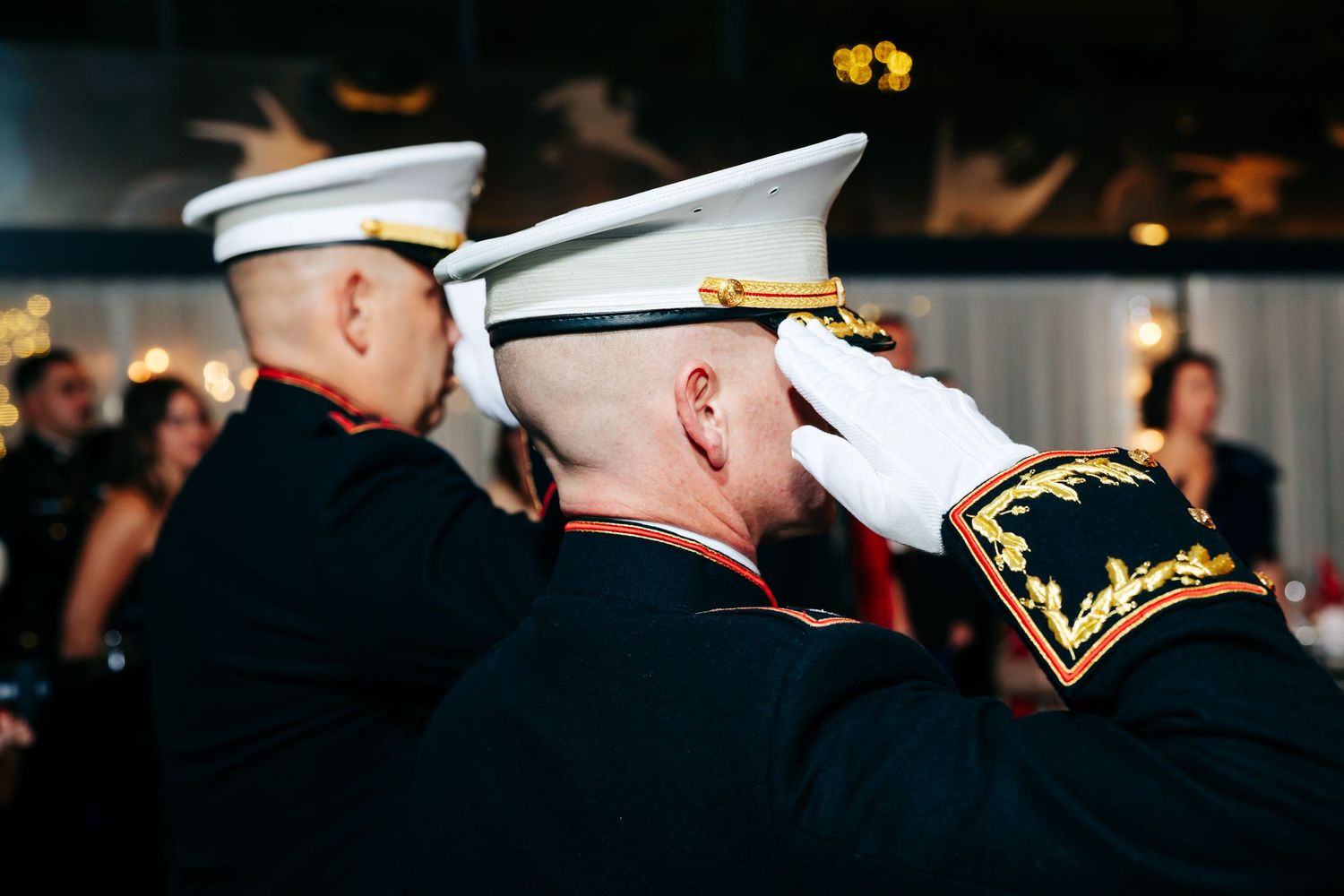 Military officers in dress uniforms saluting during a formal ceremony.