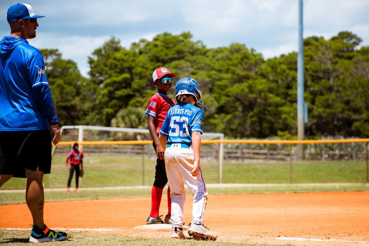 Youth baseball players and coach gathered at home plate during a game.