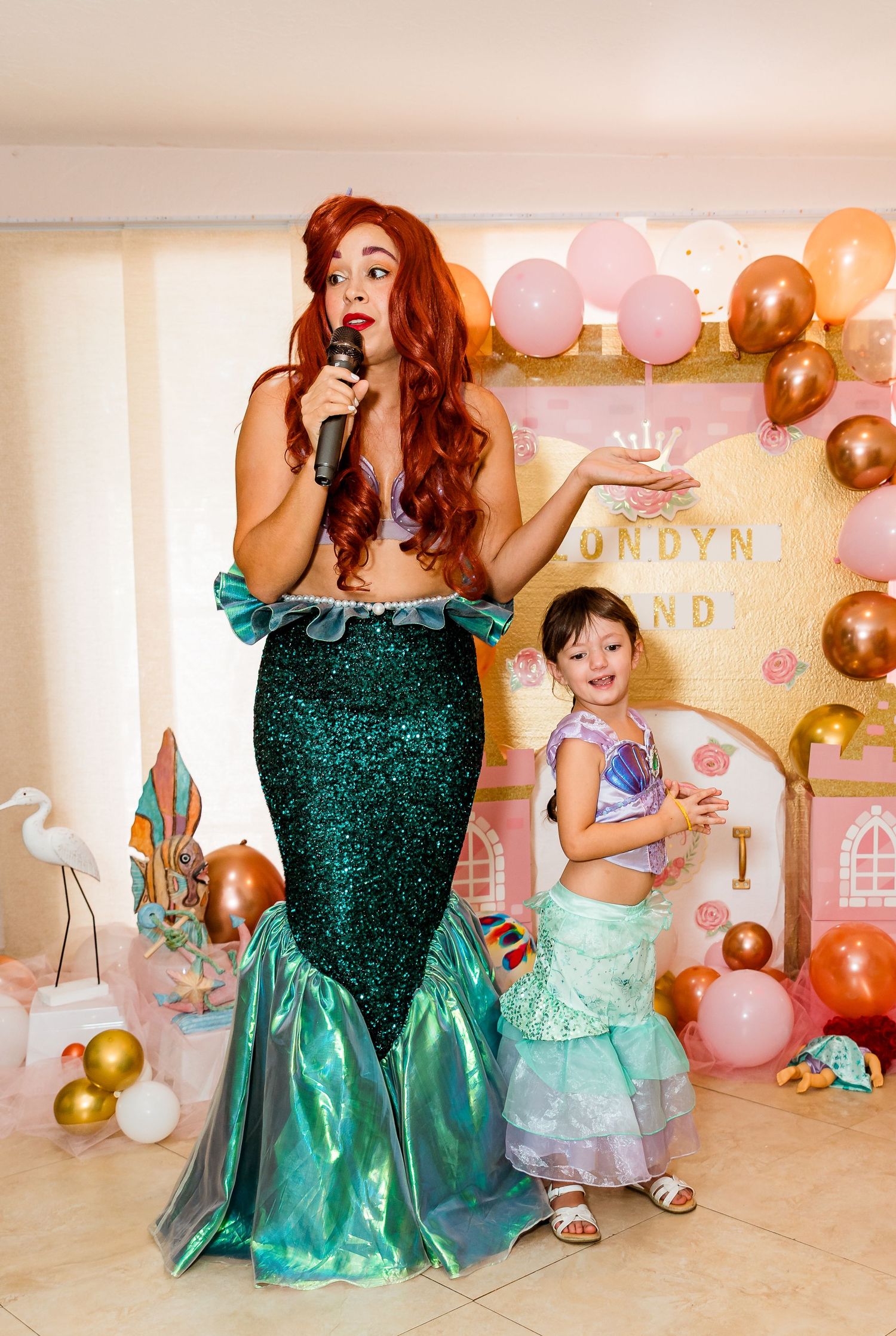 Princess themed party scene with performer in green dress and balloon decorations.