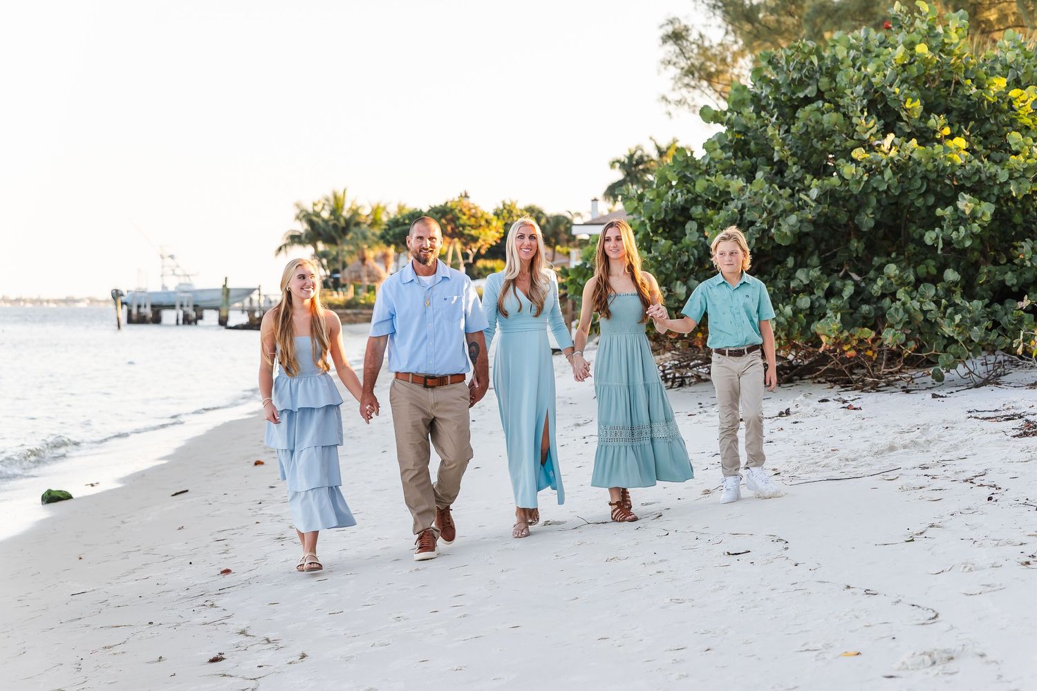 Group walking together on a sunny beach wearing coordinated blue and white outfits.