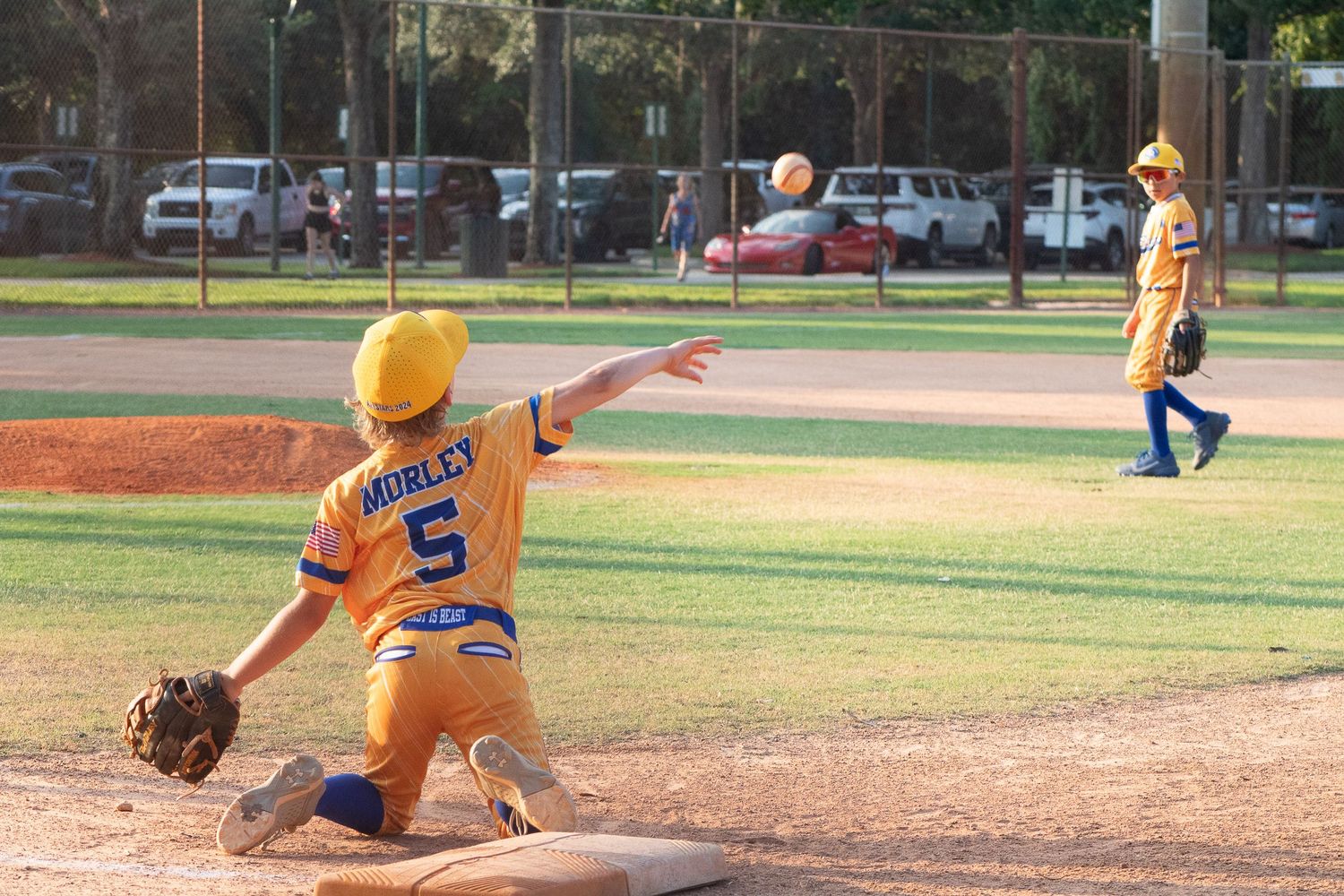 Young baseball player in yellow jersey wearing number 5 makes a play on the baseball field.